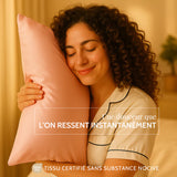 Femme aux cheveux bouclés câlinant une taie en soie rose SilkDream™ — douceur instantanée et tissu certifié OEKO-TEX® sans substance nocive.